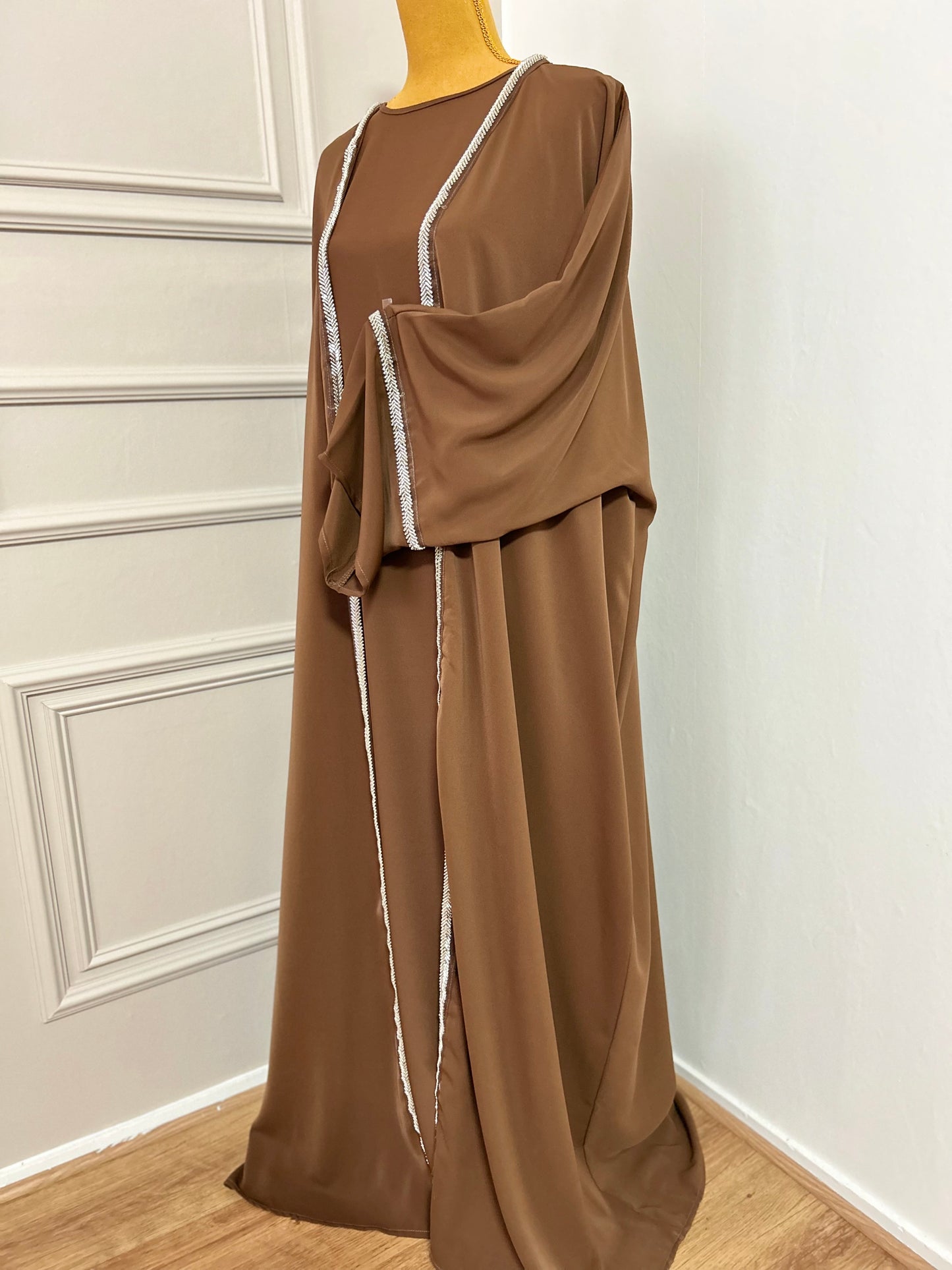 Craquez pour cette abaya marron 2 pièces alliant confort et élégance, avec son kimono orné de strass et sa sous-robe fluide. Idéale pour les occasions ou un style raffiné au quotidien.