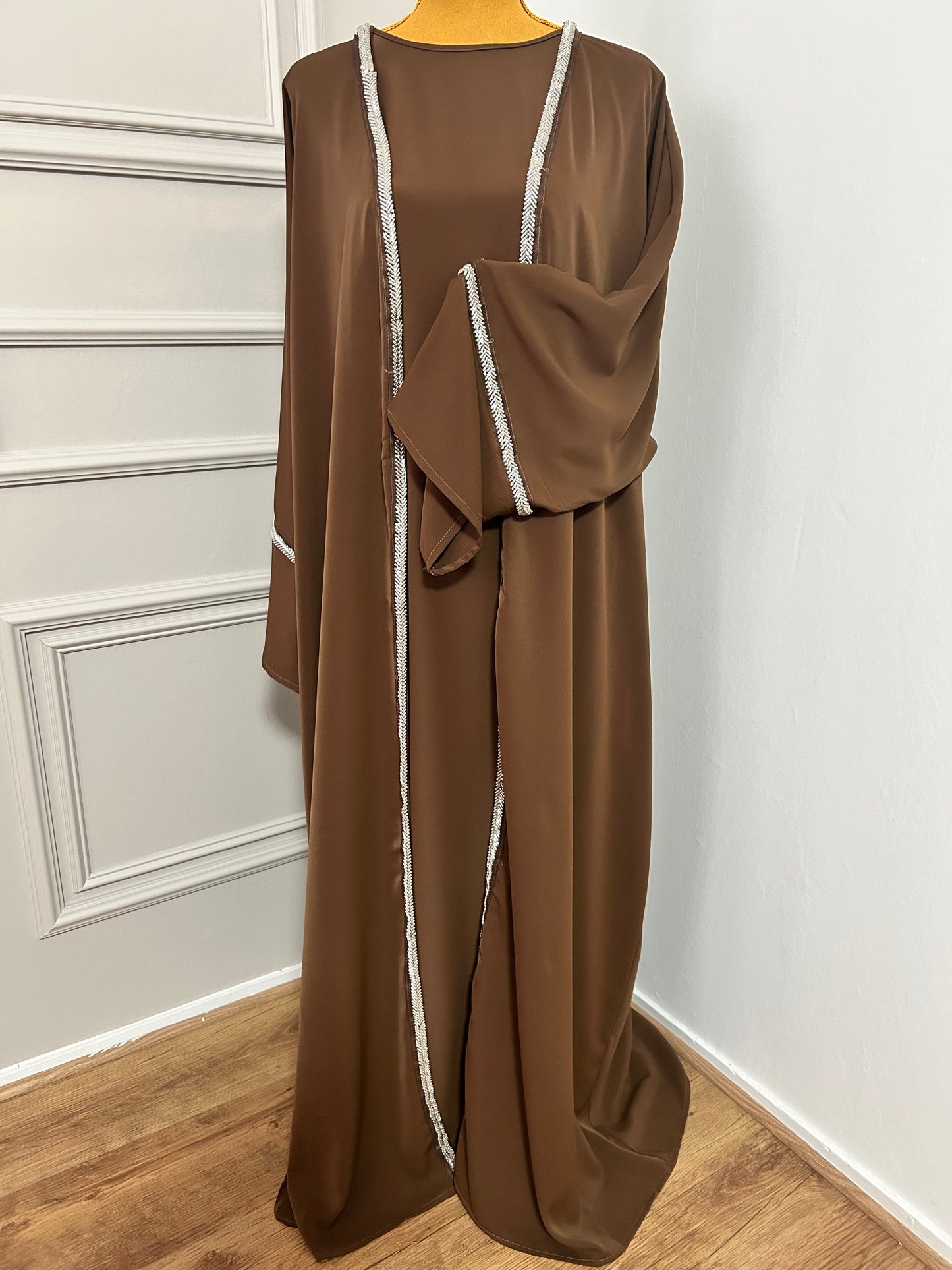 Craquez pour cette abaya marron 2 pièces alliant confort et élégance, avec son kimono orné de strass et sa sous-robe fluide. Idéale pour les occasions ou un style raffiné au quotidien.
