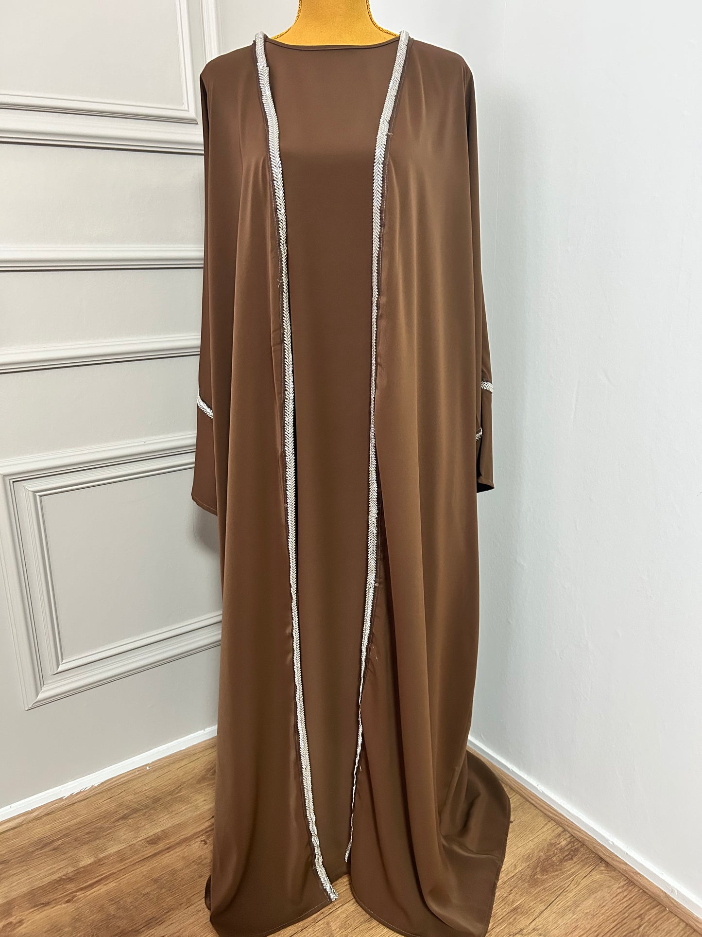 Craquez pour cette abaya marron 2 pièces alliant confort et élégance, avec son kimono orné de strass et sa sous-robe fluide. Idéale pour les occasions ou un style raffiné au quotidien.
