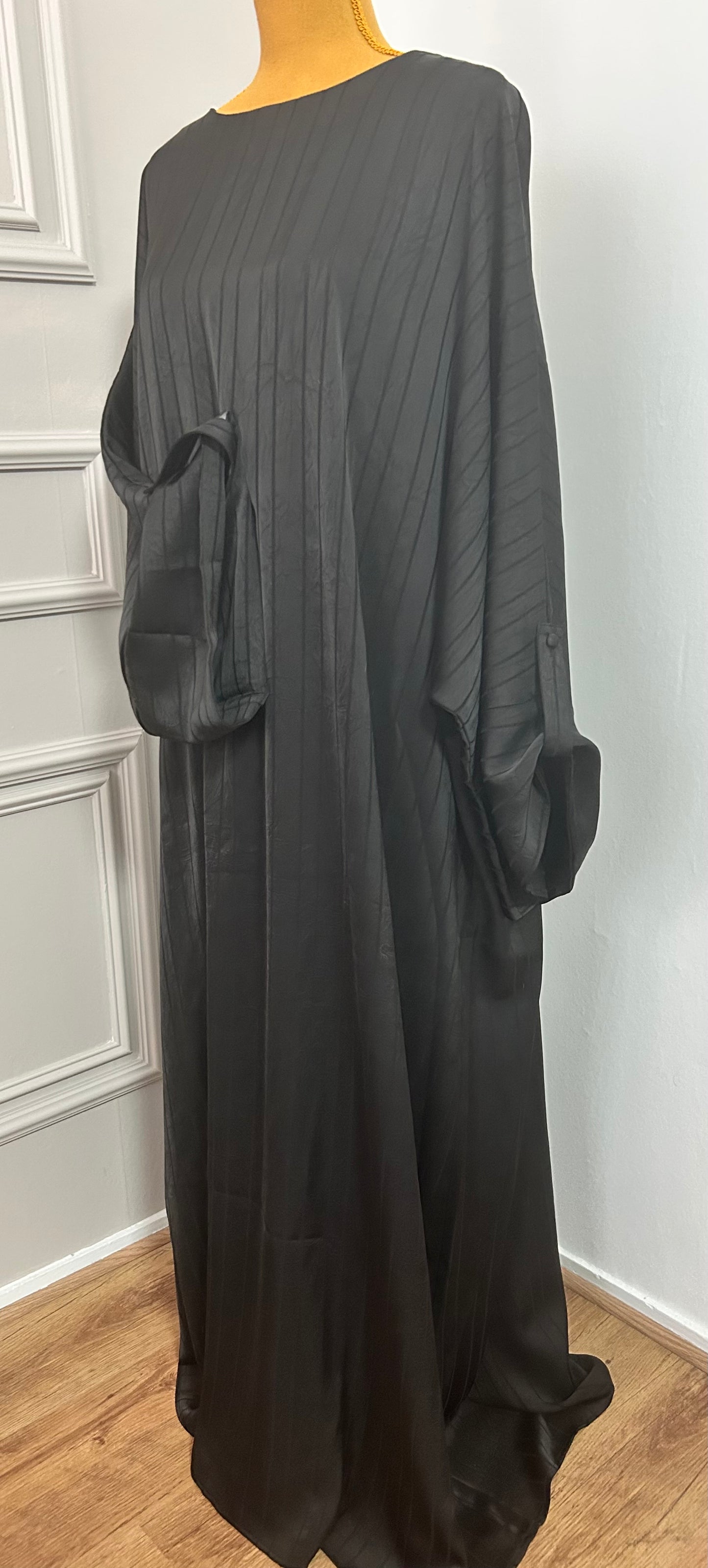 Abaya satinée noire pour femme, coupe longue et fluide, tissu texturé, manches longues, col rond.